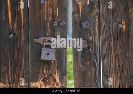 old wooden gate with rusty padlock. Background Stock Photo