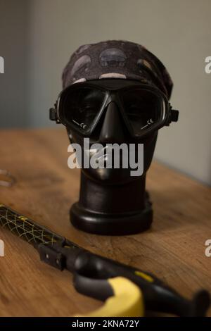 https://l450v.alamy.com/450v/2kna72y/a-vertical-shot-of-a-spearfishing-tool-and-a-diving-mask-on-a-mannequins-head-2kna72y.jpg