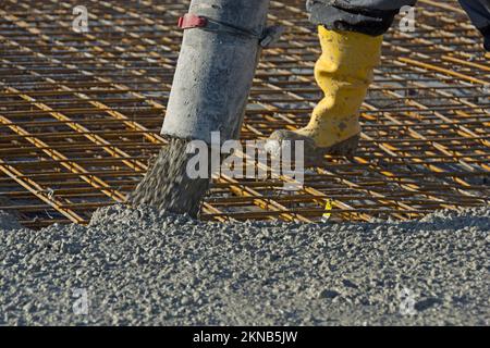 Construction worker pours concrete on rebar using concrete pump Stock Photo