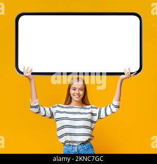 Great Offer. Beautiful Young Woman Holding Big Blank Smartphone Above Head Stock Photo