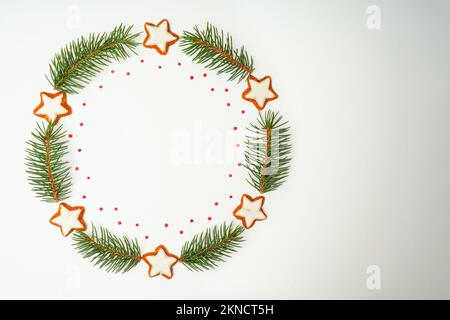 Christmas composition. Christmas wreath out of fir branches and star shaped cookies on white background. Flat lay, top view, copy space Stock Photo