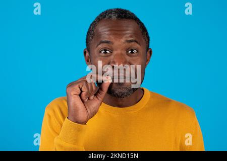 Black man showing mouth shut as zip with fingers Stock Photo