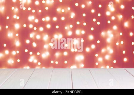 Abstract blurred background, defocused red blurred lights Bokeh on black background and white wooden surface. Glittering, glow circle pattern. Festive Stock Photo