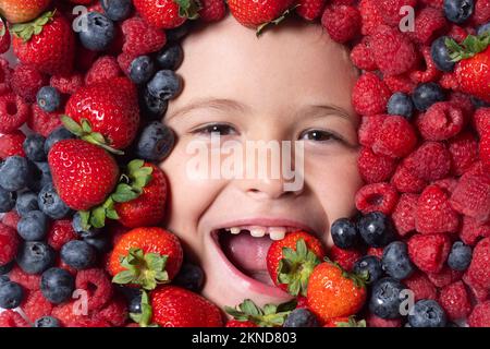 Vitamins from berrie. Mix of berries. Kids face with fresh berries fruits. Assorted mix of berries strawberry, blueberry, raspberry, blackberry on Stock Photo