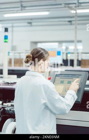 Woman on control compute of assembly line Stock Photo