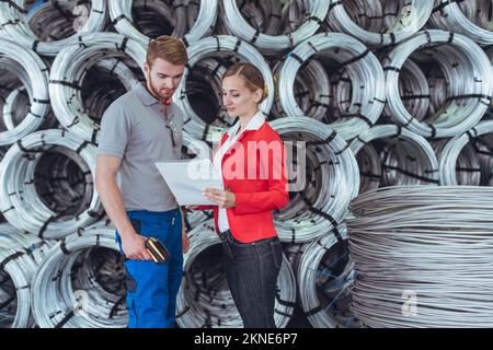 Worker and manager discussing inventory list of materials in warehouse Stock Photo