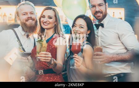 Two young couple with cocktails glasses posing in bar Stock Photo