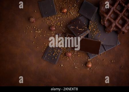 Composition of bars and pieces of different milk and dark chocolate, grated cocoa brown background top view close up Stock Photo