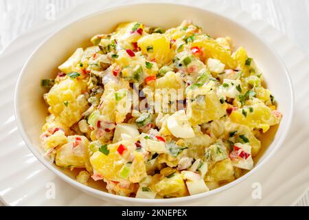 hallelujah potato salad with pickles, celery, eggs, jalapeno and mayonnaise dressing in white bowl on wooden table, close-up Stock Photo