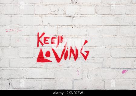 keep loving graffiti or wall art on white painted brick wall Stock Photo