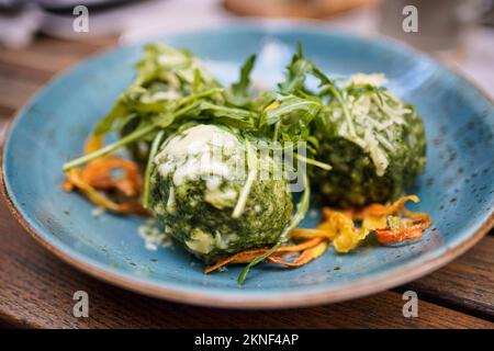 Close up of spinach dumplings with melted butter topped with mountain cheese and vegetables. Stock Photo