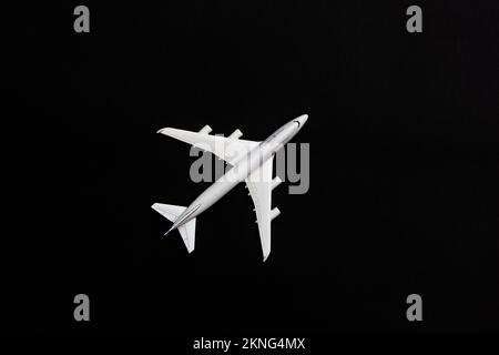 A white plane isolated on a black background. Tourism and travel concepts. Stock Photo