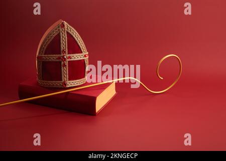 6th december Saint Nicholas Day - Sinterklaas. St Nicholas mitre and book on red table Stock Photo