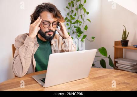 Stressed tired businessman suffering from headache working from home - Worried male entrepreneur Stock Photo
