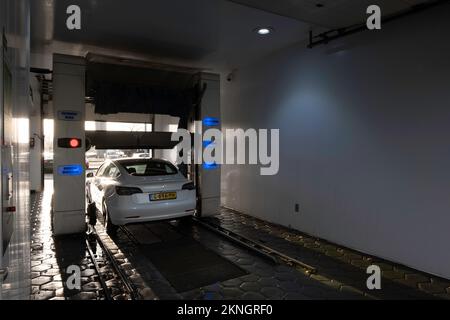 Tesla car is washed in a covered automatic car wash. Car washing. On the right side space for text or design. Rotating brushes above the car Stock Photo