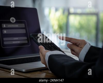 Two factor authentication or 2FA and cyber security concept. Lock icon and numbers on smartphone screen in hand, access password to laptop, identity v Stock Photo