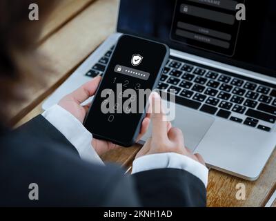 Two factor authentication or 2FA and cyber security concept. Shield icon and numbers on smartphone screen in hand, access password to laptop, identity Stock Photo