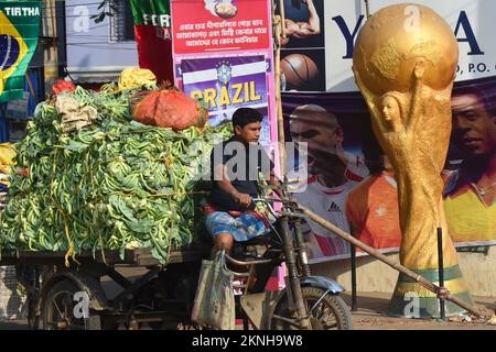 Kolkata, West Bengal, India. 27th Nov, 2022. A vegetable seller passes next to a huge football World cup Trophy replica on the roadside during the FIFA World cup 2022 in Kolkata. (Credit Image: © Sudipta Das/Pacific Press via ZUMA Press Wire) Stock Photo