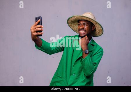 A cheerful African American man in a green shirt using mobile phone Stock Photo