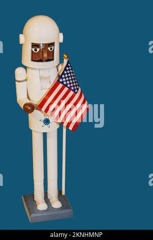 Black Astronaut Christmas Nutcracker figure with American flag isolated on blue- Room for copy Stock Photo