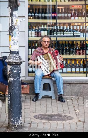 July 15 Tbilisi Georgia - Man sitting on stool in front of wine store playing accordion in Old Town Stock Photo
