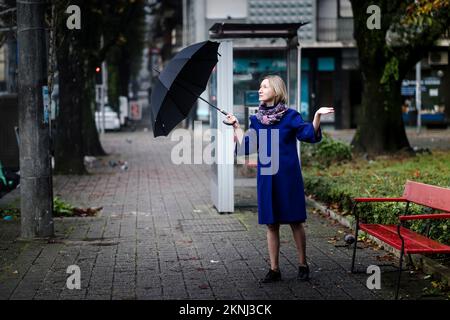 A woman with an umbrella is outside checking for rain. Stock Photo