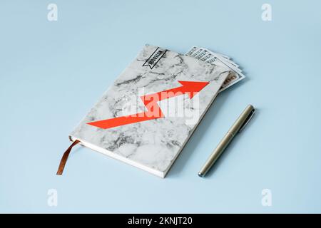 Rising cost of living, inflation, financial, economic crisis. Notebook with dollars paper money cash bills and red arrow rising up on blue background. Stock Photo