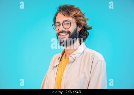 Young handsome man with beard and glasses over blue background happy face smiling looking at the camera. Positive person. Stock Photo