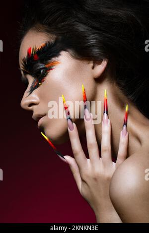 Beautiful girl in the image of the Phoenix bird with creative makeup and long nails. Manicure design. The beauty of the face. Photos shot in studio Stock Photo