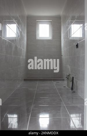New bathroom after renovation without furniture and plumbing. Water taps and holes for sewage Stock Photo