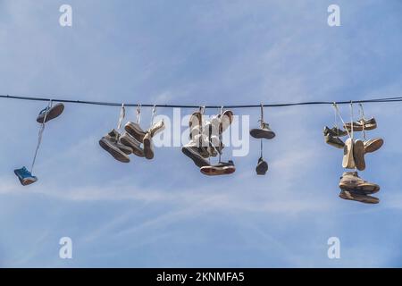 Old worn-out shoes hang from wires in slovenia Stock Photo