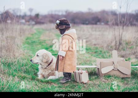 Charming sad baby in aviator's clothes says goodbye to the dog  Stock Photo