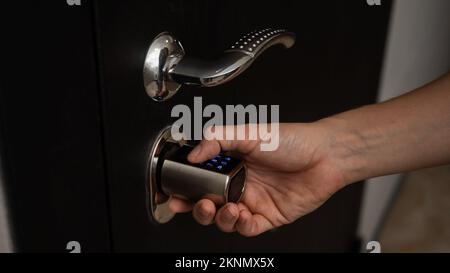 Woman opens the combination lock on the door to the apartment. Keyless entry.  Stock Photo