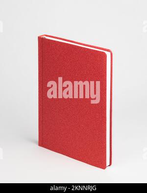 Red blank diary in standing view on table on white background. Stock Photo