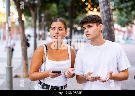Young couple using smartphones while walking Stock Photo