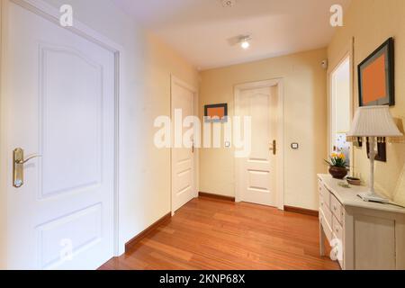 Distributor corridor of urban housing with jatoba wood parquet floors and white lacquered wood access doors to the rooms Stock Photo