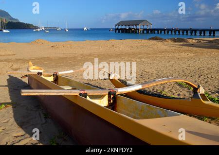 An outrigger rests on a tranquil beach on Hanalei Bay, Kauai Stock Photo