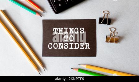 Selective focus of a pen, paper clips and notebook written with Things To Consider on wooden background Stock Photo