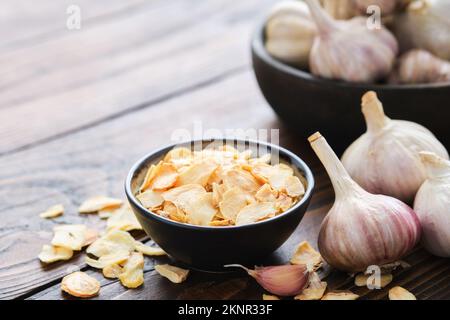 Bowl of dried garlic flakes. Garlic cloves and heads. Stock Photo