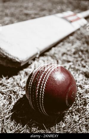 Tone vintage still-life photo of a worn red cricket ball and wood bat. Historical sports Stock Photo