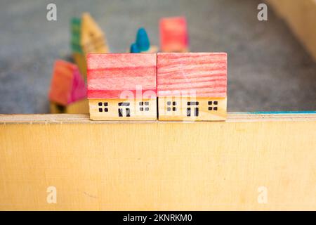 TwoCottages with red roof on grey soil. small wooden toy houses on border. Children game. Modelling village. Construction and architectural concept Stock Photo