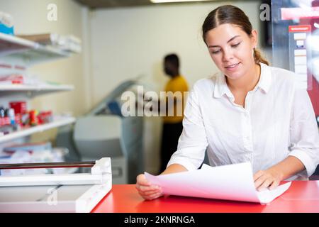 Portrait of an attentive woman checking quality of printing in printing house Stock Photo