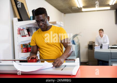 Employee of printing house checks the quality of printing in computer room Stock Photo