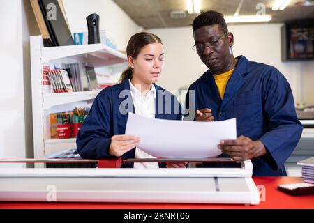 Cheerful multiracial coworkers checking the print quality and accepting color proofs in the printing house Stock Photo