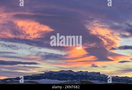 Sunset over the Absaroka Mountains on the Eastern side of Yellowstone National Park looks like fire in the sky with clouds swirling. Stock Photo