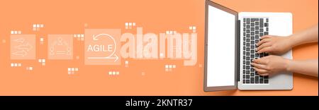 Female hands with modern laptop on orange background. Concept of agile Stock Photo