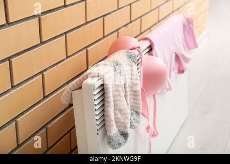 Female clothes drying on electric radiator near brick wall, closeup Stock Photo