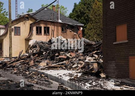 Fire damaged cottage style home next to remnants of burnt down commercial building. Stock Photo