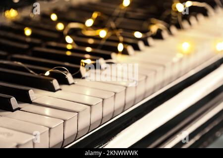 Piano keys with glowing Christmas lights, closeup Stock Photo