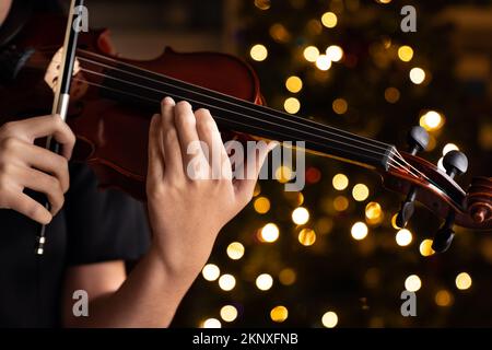 Teen playing violin in formal wear on christmas background Stock Photo